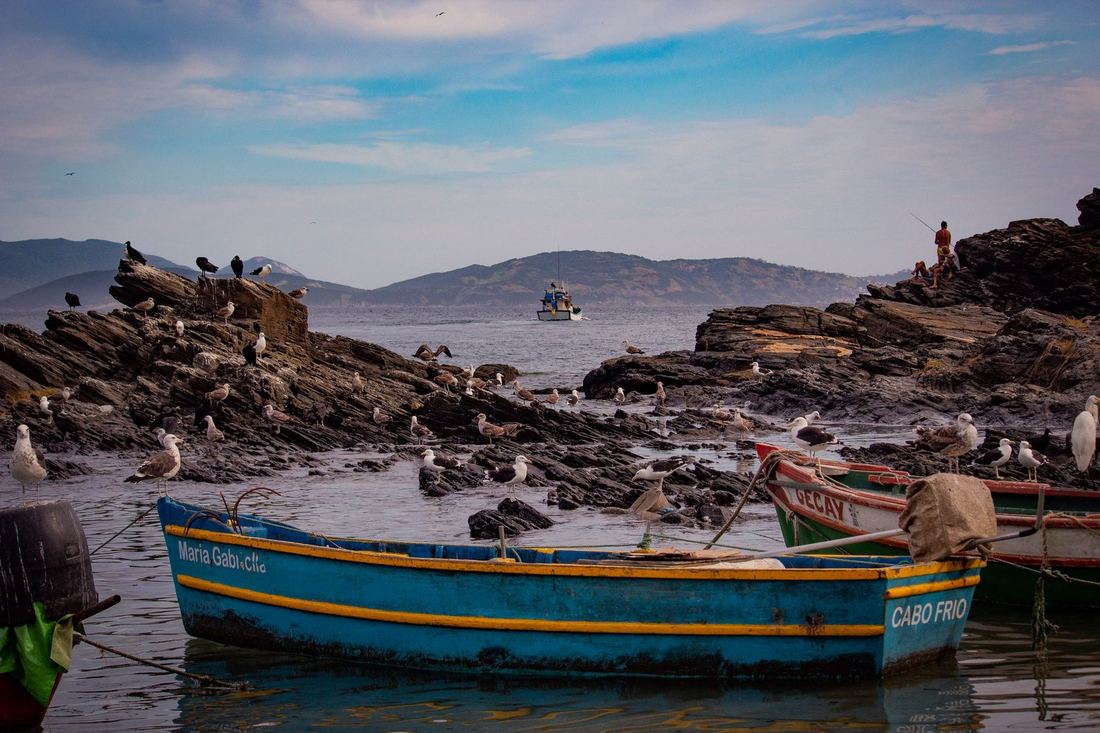 A wooden boat on the water beside a rocky coastline